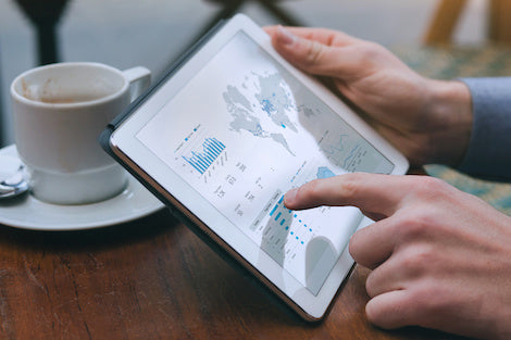 A person using a tablet that shows analytics on a tablet screen