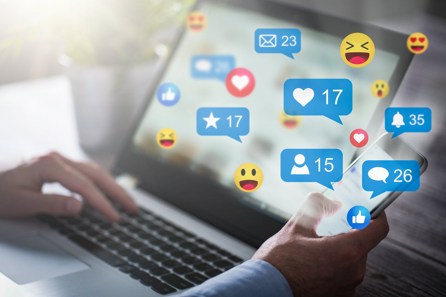 A person sitting at their computer and holding their phone with social media icons and likes popping up around their devices